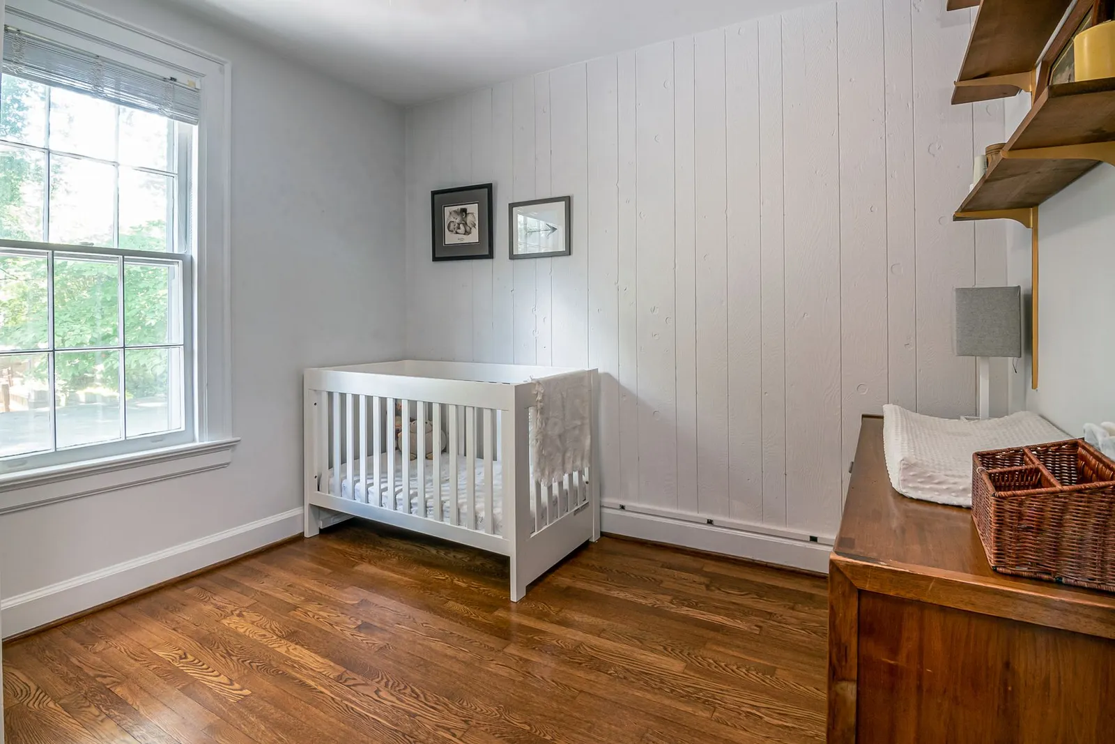 A nursery with a crib in bright window light, ready and waiting